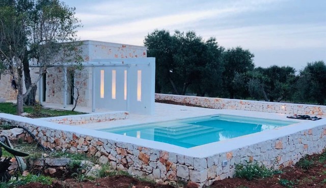 White stone typical apulian villa with barrel roof surrounded by olive trees.